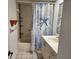 Bathroom features a decorative shower curtain, tiled walls and floors, and vanity sink at 4912 Enfield Ct, New Port Richey, FL 34655