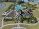 Aerial view of the community clubhouse and a stunning, clover-shaped pool surrounded by palm trees and lounge chairs at 13822 Bee Tree Ct, Hudson, FL 34669