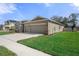 A neutral-toned, single-story home with stone accents and a wide driveway leading to an attached two-car garage at 13822 Bee Tree Ct, Hudson, FL 34669