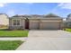 Charming single-story home featuring a red front door, neutral paint, stone accents, and an attached two-car garage at 13822 Bee Tree Ct, Hudson, FL 34669