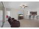 Comfortable living room boasts tile flooring, a stylish fan, and an open view to the kitchen with bar seating at 13822 Bee Tree Ct, Hudson, FL 34669