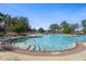 Community pool with shallow end, lounge chairs, lush landscaping, and a serene atmosphere at 13822 Bee Tree Ct, Hudson, FL 34669