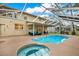 Backyard pool and hot tub with a screened-in enclosure and outdoor seating area at 9617 Norchester Cir, Tampa, FL 33647