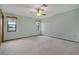 A well-lit bedroom features neutral carpet, ceiling fan and a pair of windows providing natural light at 10200 Sunburst Ct, Spring Hill, FL 34608
