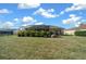 Expansive fenced backyard showing the house and pool with a screened enclosure, set against a backdrop of lush greenery at 14215 Presteign Ln, Spring Hill, FL 34609