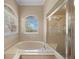 A bathroom with a soaking tub and shower featuring tile floors and natural light at 14215 Presteign Ln, Spring Hill, FL 34609