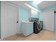Laundry room with blue walls and cabinets, as well as tile floor and new washer and dryer at 14215 Presteign Ln, Spring Hill, FL 34609