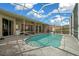 A refreshing in-ground pool is encased in a screened enclosure with an outdoor living space at 14215 Presteign Ln, Spring Hill, FL 34609
