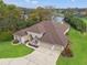 Stunning aerial view of a lakeside home with a lush green lawn and a spacious three-car garage at 4412 Lake In The Woods Dr, Spring Hill, FL 34607