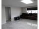Open living room featuring gray tile floors, bright lighting, and a comfortable leather sofa at 5641 Quist Dr, Port Richey, FL 34668