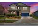 Charming two-story home featuring a well-manicured lawn, vibrant flower beds, and a stylish blue garage door at 9173 Shadyside Ln, Land O Lakes, FL 34637