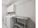 Bright laundry room features a washer, dryer, storage, and a stainless steel utility table at 9173 Shadyside Ln, Land O Lakes, FL 34637