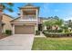 Charming two-story home with a balcony, attached two-car garage, and well-manicured lawn with mature palm trees at 9323 Bella Vita Cir, Land O Lakes, FL 34637