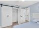 Bedroom featuring barn doors, blue walls, and access to the bathroom at 14124 Kulig Ct, Hudson, FL 34667