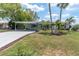 Charming home featuring a carport, a well-manicured lawn, and lush landscaping with palm trees at 14124 Kulig Ct, Hudson, FL 34667