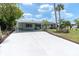 Charming single-story home with a covered carport and large concrete driveway and tropical landscaping at 14124 Kulig Ct, Hudson, FL 34667
