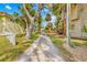 Long gravel driveway framed by mature trees and tropical plants leading to the house at 8711 Betty St, Port Richey, FL 34668