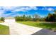 Exterior shot of the garage featuring a driveway, a well-manicured lawn, and mature trees at 10030 Orchard Way, Spring Hill, FL 34608