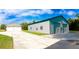 Exterior shot of the garage and additional building featuring a driveway, a well-manicured lawn, and mature trees at 10030 Orchard Way, Spring Hill, FL 34608