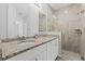 Bathroom showcasing double vanity, granite countertops, tiled shower with glass door, and a linen closet at 13094 Tailorbird Ave, Brooksville, FL 34614