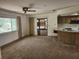 Spacious living room featuring carpeted floors, sliding door access to the backyard, and a view into the kitchen at 12501 Shadow Ridge Blvd, Hudson, FL 34669