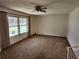 Bright living room with large window, neutral walls, carpeted flooring, and a ceiling fan at 12501 Shadow Ridge Blvd, Hudson, FL 34669