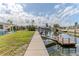 Waterfront backyard with a concrete walkway leading to a wooden dock on a serene canal at 13705 Allyn Dr, Hudson, FL 34667