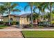 Charming home with a well-manicured front yard, vibrant flowers, palm trees, and a brick-paved driveway at 20200 Lace Cascade Rd, Land O Lakes, FL 34637