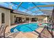 Backyard pool with an attached spa, summer kitchen, travertine patio, and a screened-in enclosure at 20200 Lace Cascade Rd, Land O Lakes, FL 34637