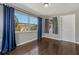Bedroom featuring hardwood floors, windows with curtains, and a door, with a view of the backyard at 3540 Linkwood St, New Port Richey, FL 34652