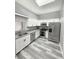 Modern kitchen featuring stainless steel appliances, white cabinets, granite countertops, and grey wood floors at 4218 San Rafael Ave, New Port Richey, FL 34655