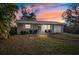 Charming single-story home with a well-maintained front yard, blue door and colorful sunset at 5973 Mckee Lake N Dr, St Petersburg, FL 33709