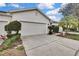 View of the front exterior featuring a two car garage, manicured shrubs and a neatly paved driveway at 7343 Cleopatra Dr, Land O Lakes, FL 34637