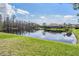 Scenic backyard view featuring a serene lake, lush green grass, and the home's exterior at 12824 Tikal Way, Trinity, FL 34655