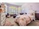 This bedroom has a light pink color scheme, plenty of light, and a comfortable chaise lounge at 12824 Tikal Way, Trinity, FL 34655