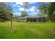 Backyard view of the home featuring a screened pool enclosure and a well-maintained lawn area at 16325 Hibiscus Rd, Brooksville, FL 34601