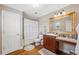Bathroom with granite counters, wood cabinets, framed mirror and shower behind ruffled curtain at 18819 Sunterra Dr, Land O Lakes, FL 34638