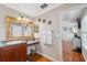 Bathroom featuring granite counters, wood cabinets, framed mirror, and access to the bedroom at 18819 Sunterra Dr, Land O Lakes, FL 34638