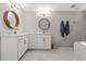 Bright bathroom featuring double vanity, round decorative mirrors, brushed gold faucets, and tub with shower at 7482 Winter St, Brooksville, FL 34613