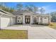 Beautiful gray house featuring large windows, white columns, an attached garage, and a sprawling driveway at 7482 Winter St, Brooksville, FL 34613