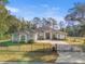 Beautiful gray house with a gated entry, an attached garage, a lush front yard, and a long driveway at 7482 Winter St, Brooksville, FL 34613