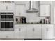 Close-up of a modern kitchen with white cabinets, stainless steel appliances, and stylish backsplash at 7482 Winter St, Brooksville, FL 34613