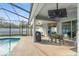 Charming screened-in patio with an outdoor dining area, grill, and tranquil view of the pool and backyard at 7482 Winter St, Brooksville, FL 34613