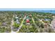 Aerial view of home in lush, green neighborhood with bay views in the distance at 1888 Douglas Ave, Dunedin, FL 34698