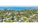 An aerial view captures a charming home, surrounded by verdant landscapes and near a serene coast at 1888 Douglas Ave, Dunedin, FL 34698