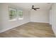 Bright bedroom featuring hardwood floors, white walls, a ceiling fan, and natural light from the windows at 1888 Douglas Ave, Dunedin, FL 34698
