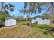 Backyard view featuring a light blue home with white trim, shed, and a fenced yard at 1888 Douglas Ave, Dunedin, FL 34698
