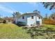 Light blue house exterior showcasing a fenced yard, green lawn, updated fence, and a modern AC unit at 1888 Douglas Ave, Dunedin, FL 34698