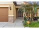 Home's inviting front entry featuring a screened front door, stacked stone details, and lush landscaping at 2109 Trillium Blvd, Brooksville, FL 34604