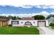 Unique home featuring a white facade, red trim, an attached garage, and a well-maintained green lawn at 3526 Overland Dr, Holiday, FL 34691